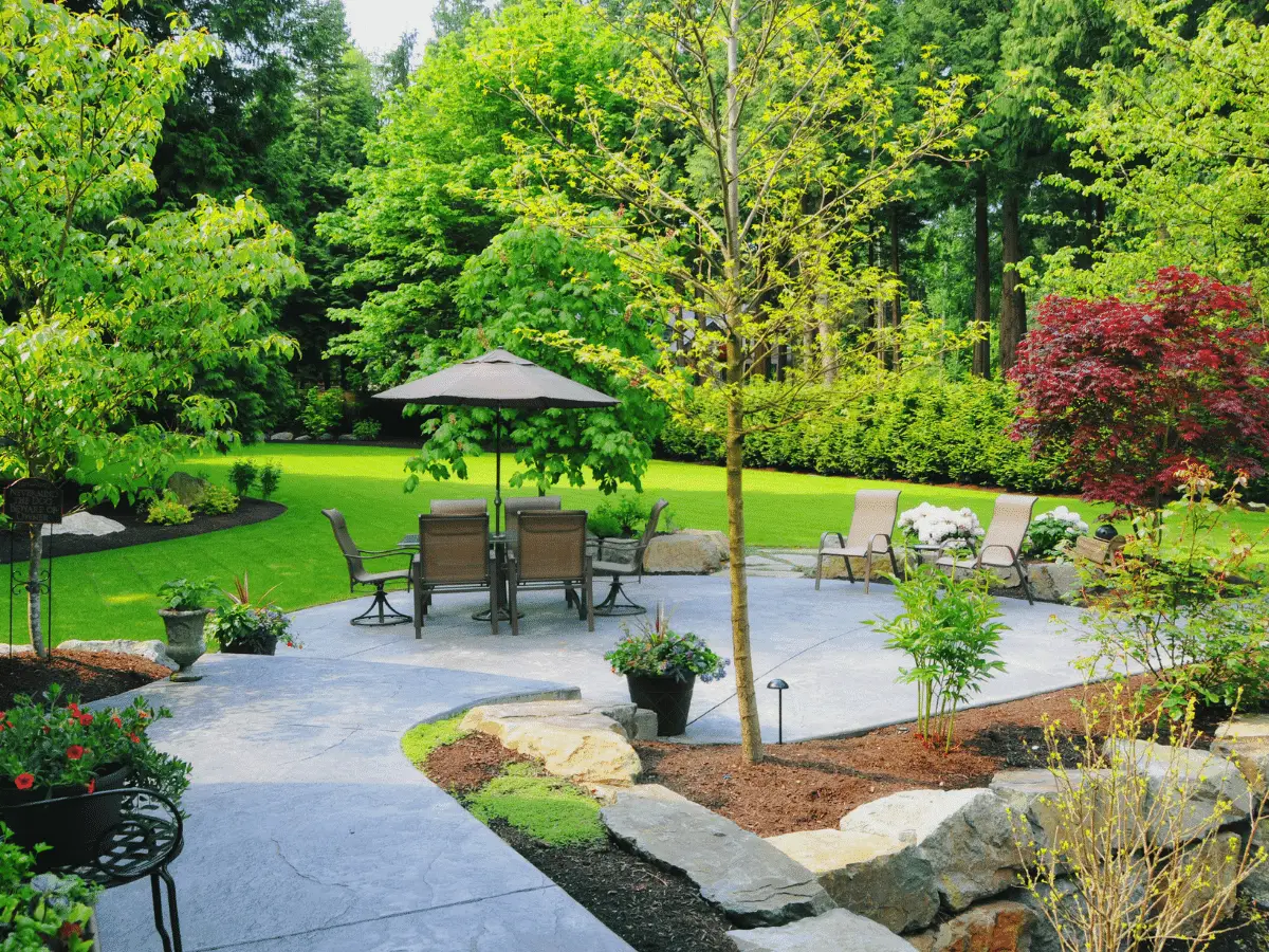 Lush garden with patio furniture and colorful trees.