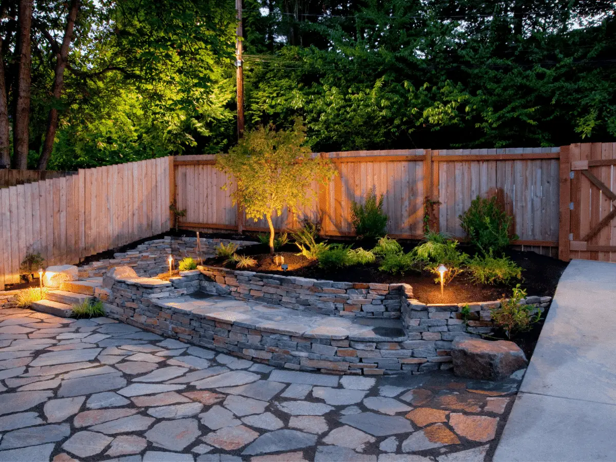 Well-lit stone patio with surrounding garden landscape