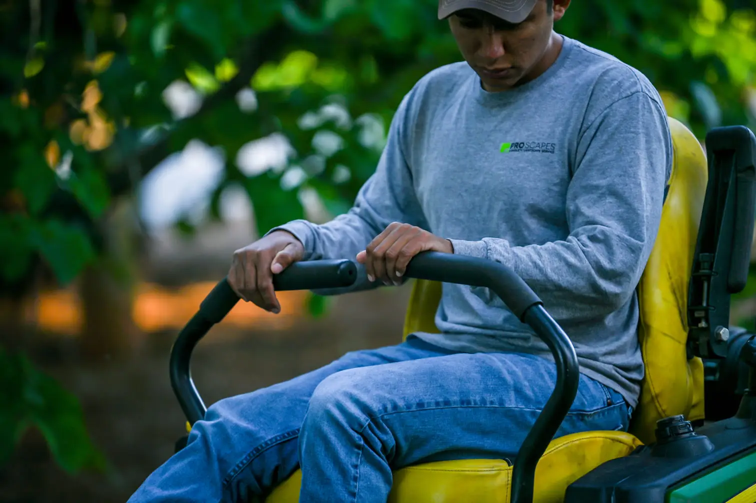 Person operating a riding lawn mower outdoors.