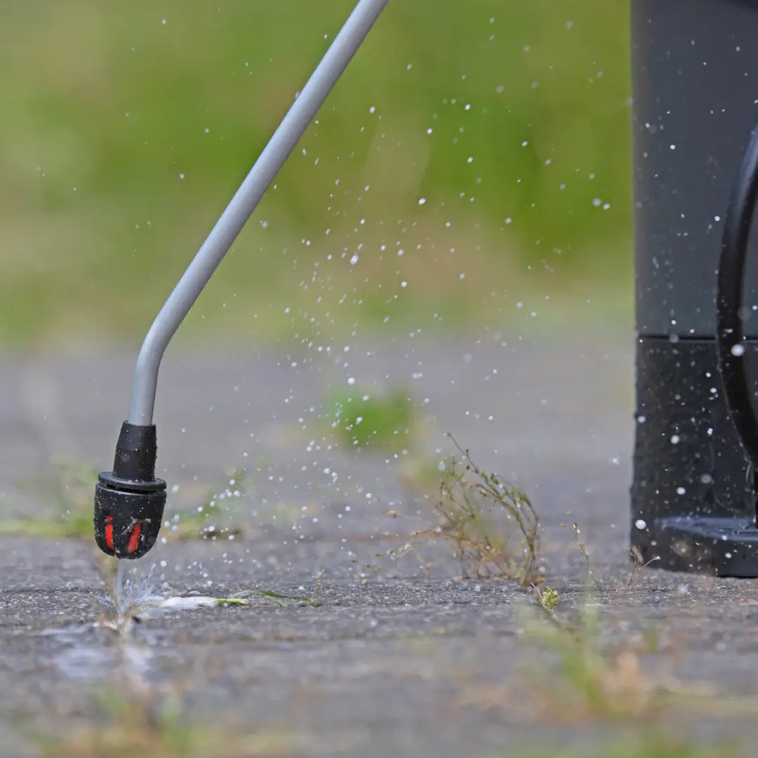 Pressure washer cleaning pavement with water spray